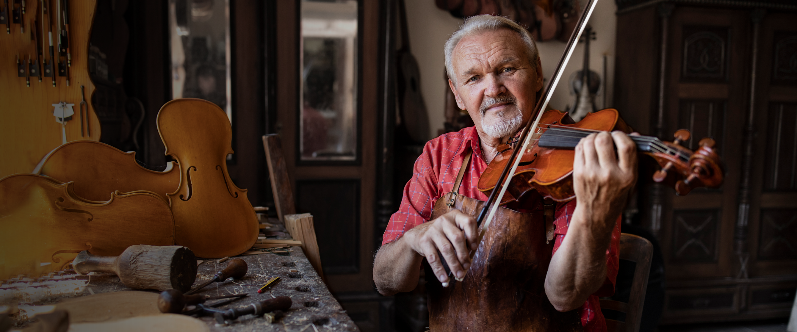 Atelier Banner - Luthier playing a violin in his shop