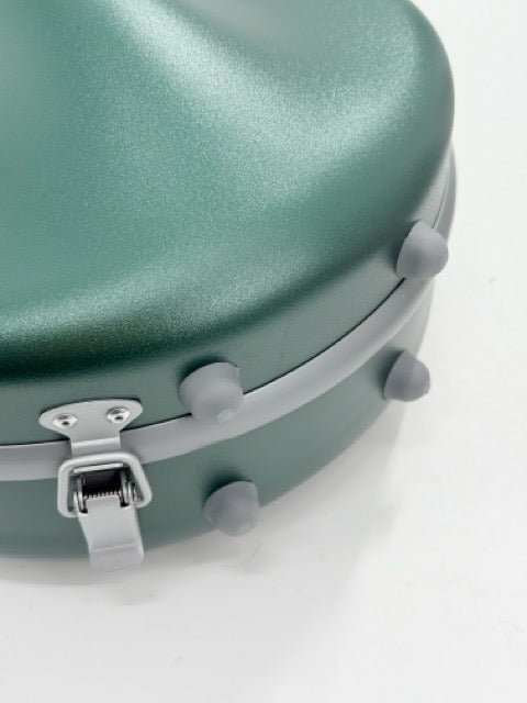 A close-up of the Artino Muse CN3804 Violin Case | 4/4 & 3/4 highlights its lightweight green polycarbonate shell, featuring a latch and four round gray rubber feet, displayed on a white surface.