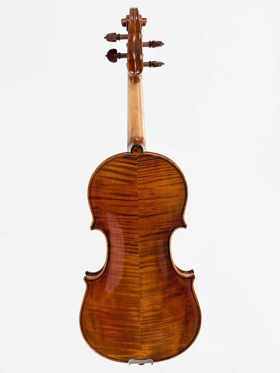 The Atelier Violin Outfit Special, a polished handcrafted violin with a rich brown wood grain and glossy finish, is shown from the back against a white background—an elegant choice for those seeking an exceptional beginner instrument.