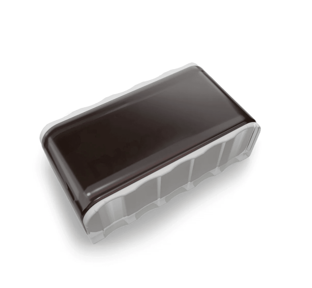 A rectangular piece of chocolate with a glossy, dark surface reminiscent of D'Addario Natural Rosin Dark, resting on a clear plastic tray, isolated on a white background.