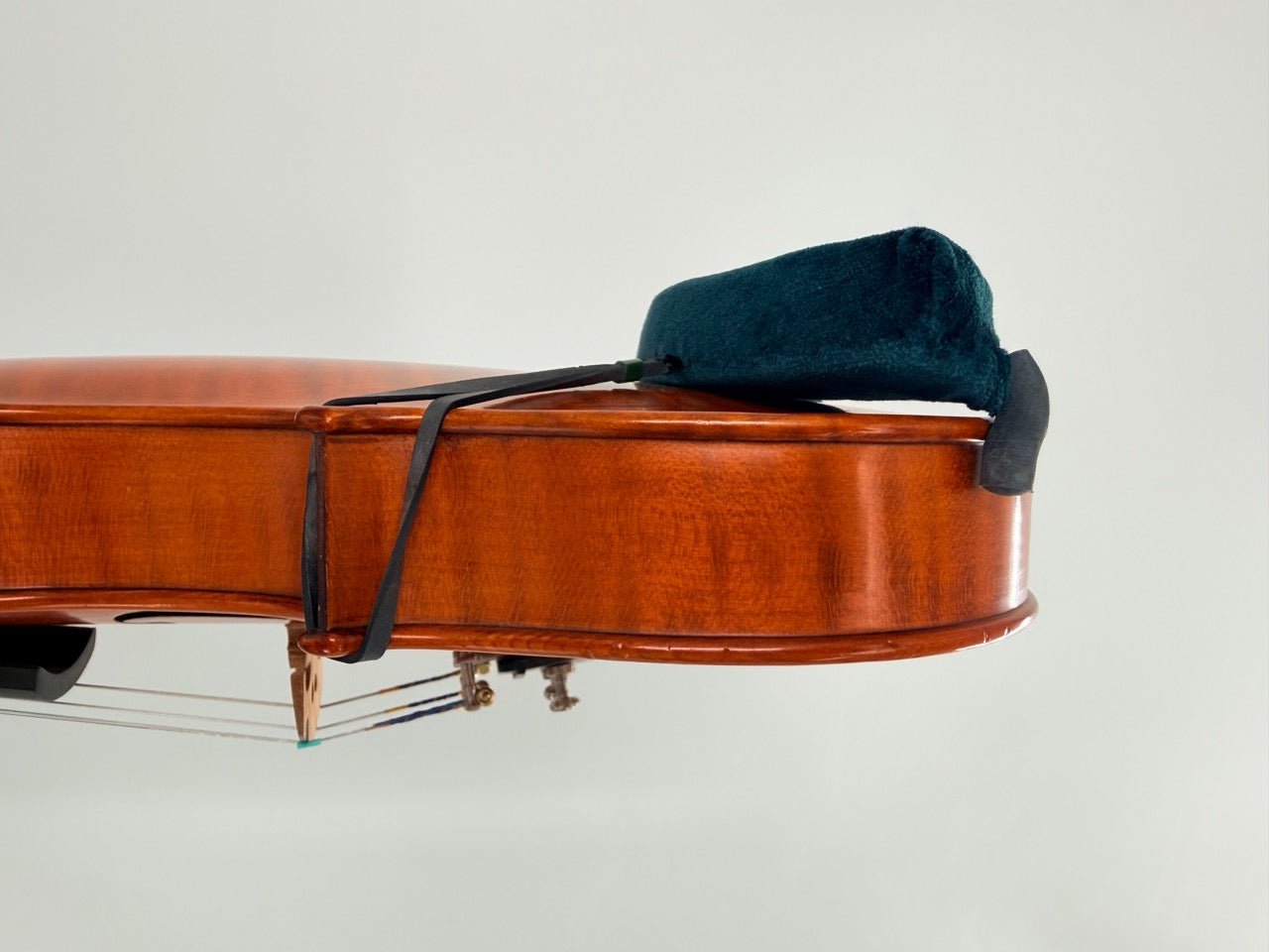 A close-up side view of a violin with the Decor / FOM Shoulder Rest for Violin attached, set against a plain light background.