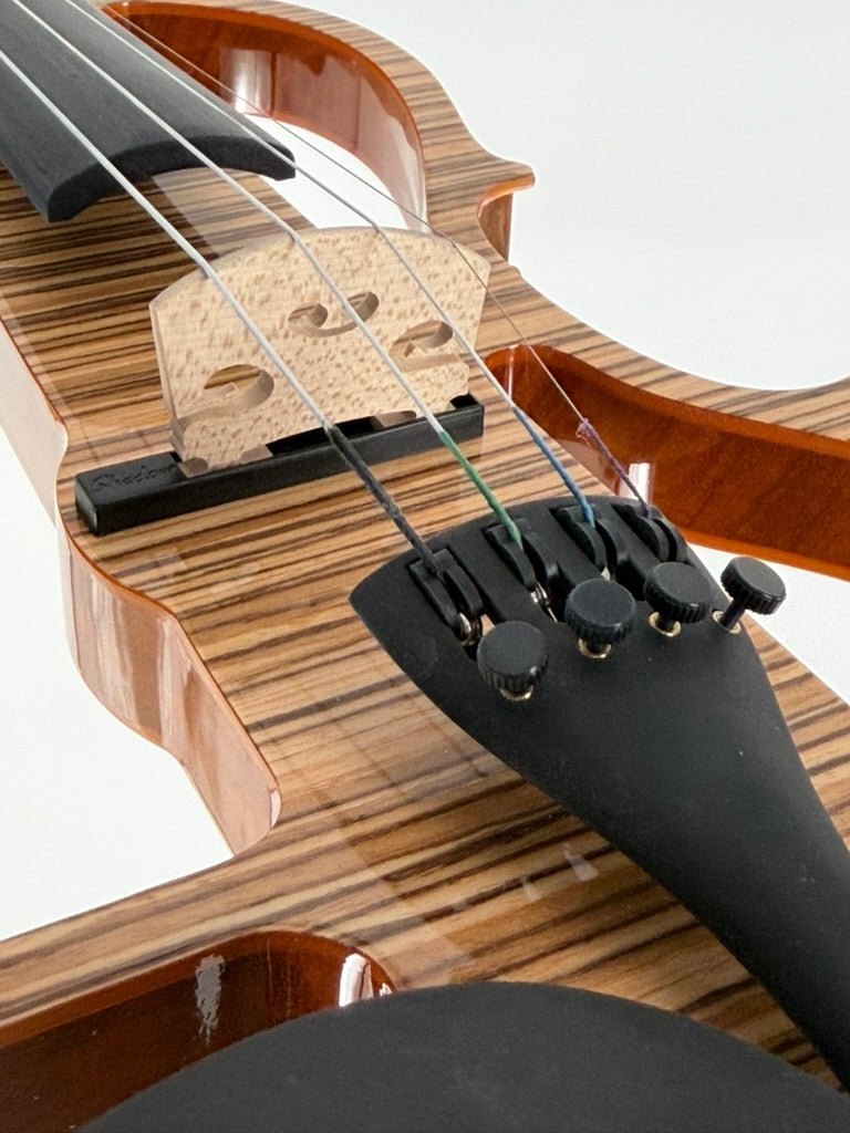 Close-up of the Geneva Electric Violin with Shadow Preamp—professionally set up at Atelier—showing its striped wood grain finish, black fittings, and fine tuners, perfect for silent practice or amplified performance against a white background.
