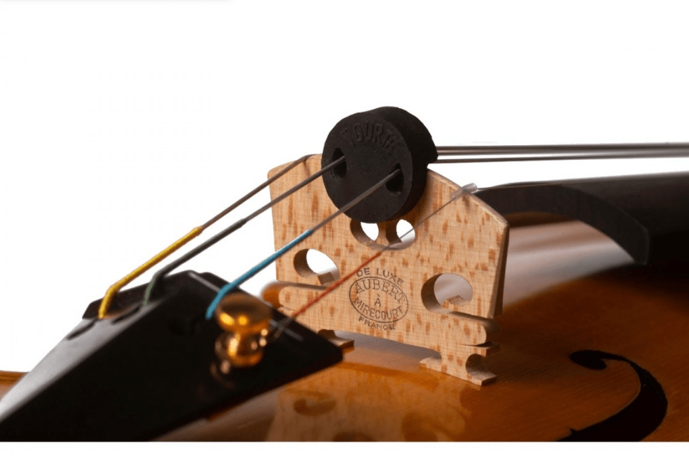 Close-up of a violin bridge with colored strings and a Goetz Tourte Round Rubber Violin & Viola Mute attached at the top, partially obscuring the bridge’s label.
