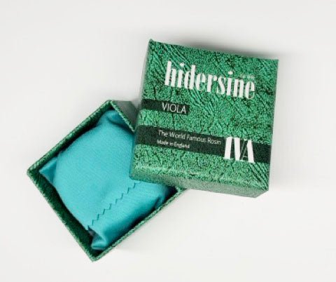A green box labeled Hidersine 1VA Viola Rosin – Light Amber, Large Cake sits open, revealing a turquoise cloth holding the light amber viola rosin inside. The package displays “The World Famous Rosin” and “Made in England,” making it an essential choice among viola accessories.