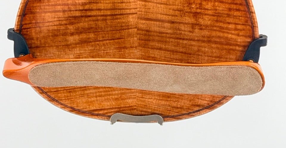 Close-up of a violin back with the Mach One MA Maple Shoulder Rest—Premium Wooden Violin Support (4/4–3/4)—featuring suede-like padding and black clamps, shown against a plain white background.
