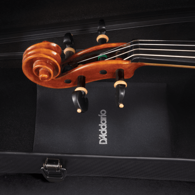 A close-up of a violin scroll and tuning pegs resting in a black case, with a D’Addario cleaning cloth partially visible underneath, showcases the care taken to protect orchestral string instruments—even more so with the discreet inclusion of the Small Instrument Humidipak Kit to maintain optimal humidity conditions.