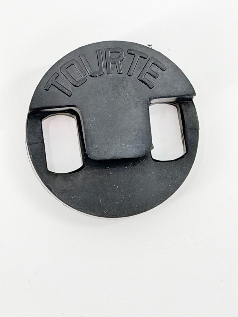 A Tourte Bass Mute, round and black with "TOURTE" embossed on top, rests on a white surface.