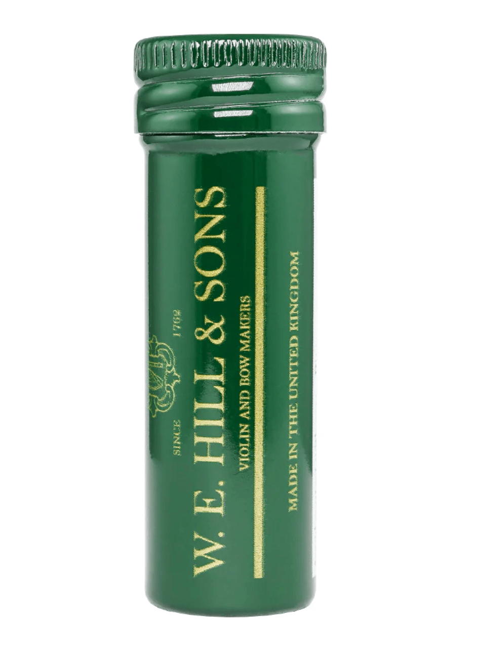 A green cylindrical container labeled “W. E. Hill & Sons Peg Compound, Made in the United Kingdom” in gold text stands upright on a white background, designed for violin peg maintenance.