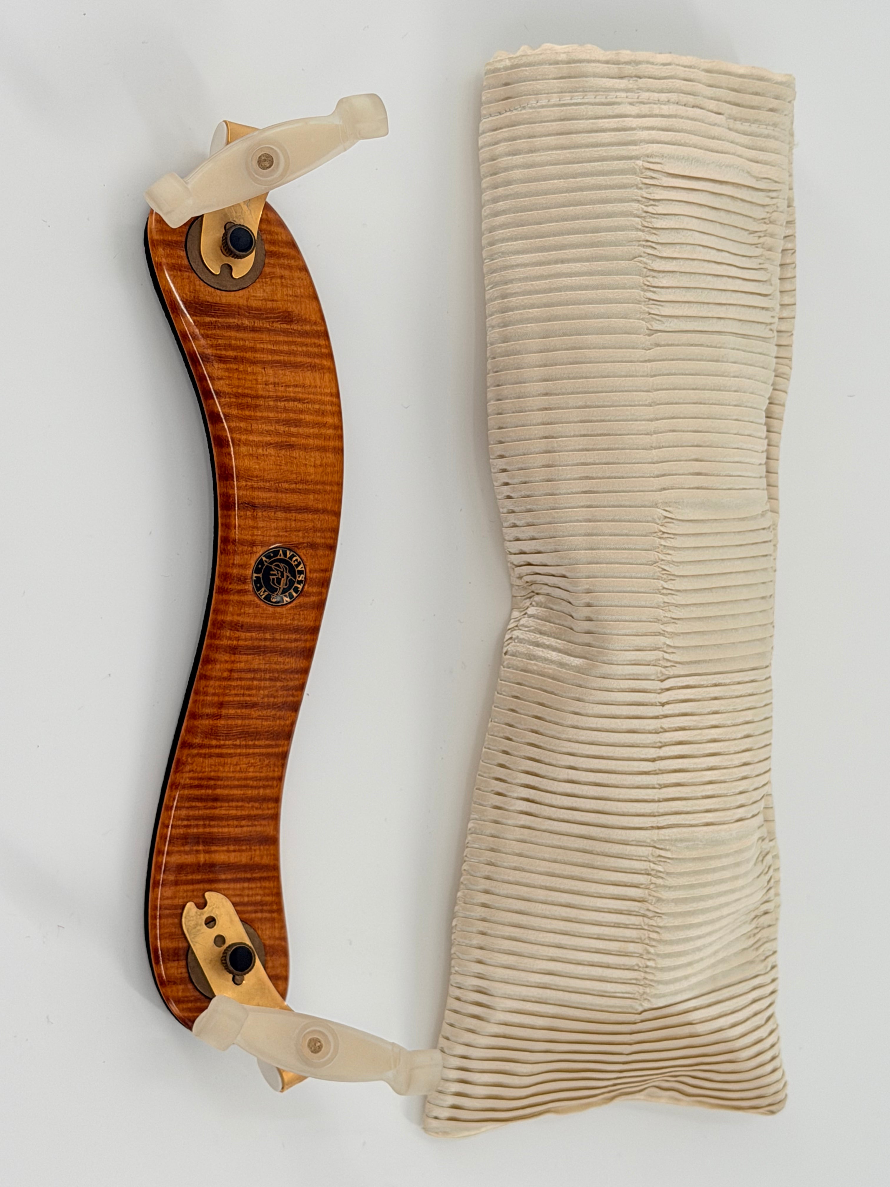 A Viva La Musica Diamond Shoulder Rest with beige rubber clamps is placed beside a padded, ribbed off-white cloth case against a white background.