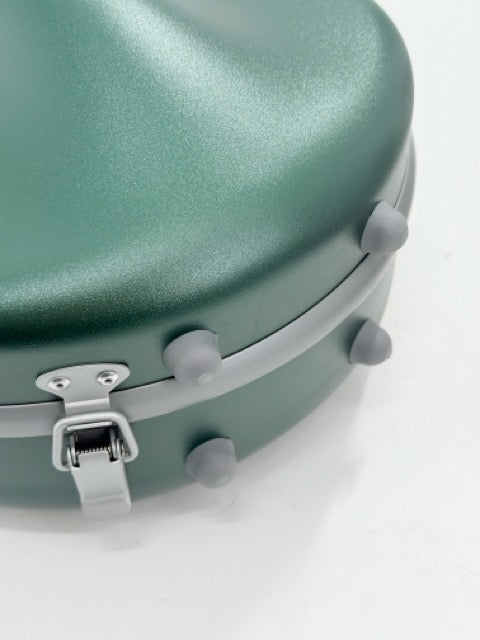 A close-up of the Artino Muse CN3804 Violin Case | 4/4 & 3/4 highlights its lightweight green polycarbonate shell, featuring a latch and four round gray rubber feet, displayed on a white surface.