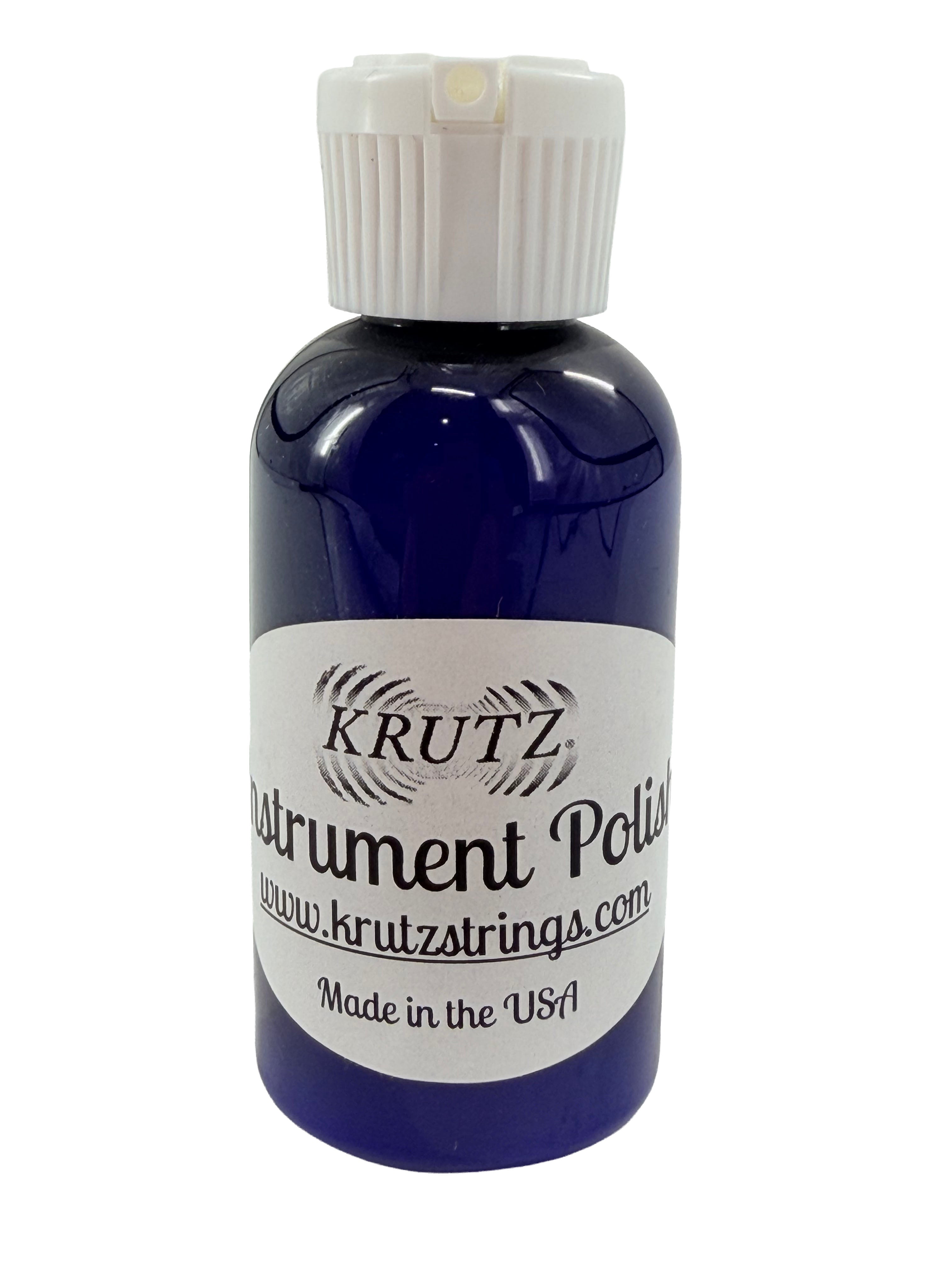 A blue bottle of KRUTZ Instrument Polish, designed as a natural cleaner for wooden musical instruments, featuring a white cap. The label displays the website www.krutzstrings.com and indicates that it is Made in the USA.