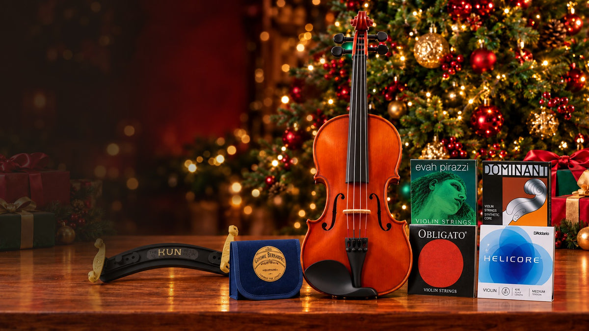 Violin with Evah Pirazzi, Dominant, Obligato and Helicore violin strings, a KUN shoulder rest and Bernardel rosin on a wooden table in front of a lit Christmas tree.
