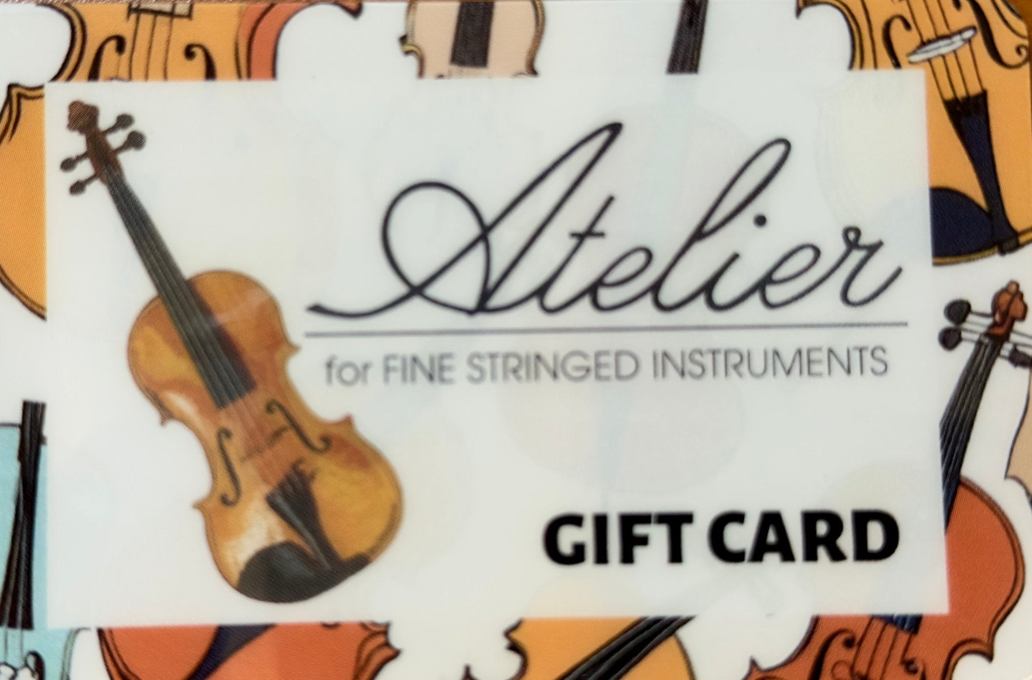 The Atelier for Fine Stringed Instruments Gift Card features a violin illustration, the store name, and a background of multiple violins, with “GIFT CARD” in bold at the bottom right.