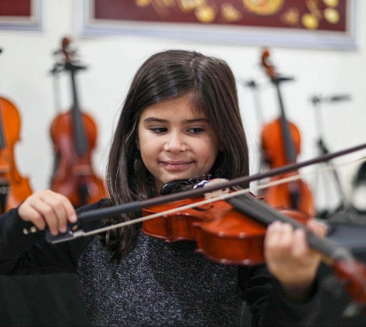 Young student smiling while playing a violin at Atelier