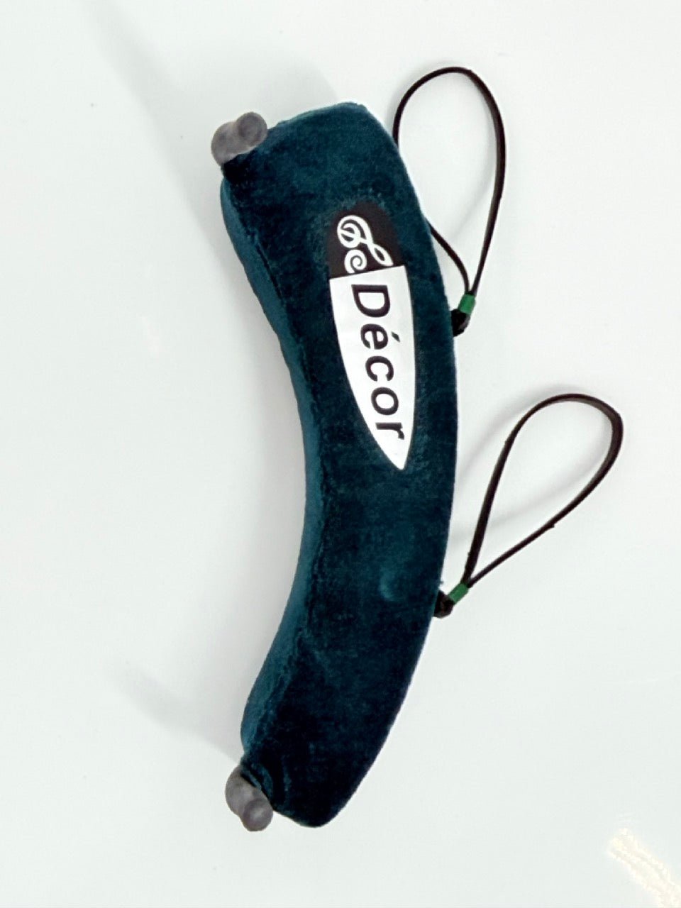 The Decor Shoulder Rest for Violin features a curved, dark green velvet cushion design with black elastic loops on each end and a central white Décor label. Lightweight, it's shown against a white background.