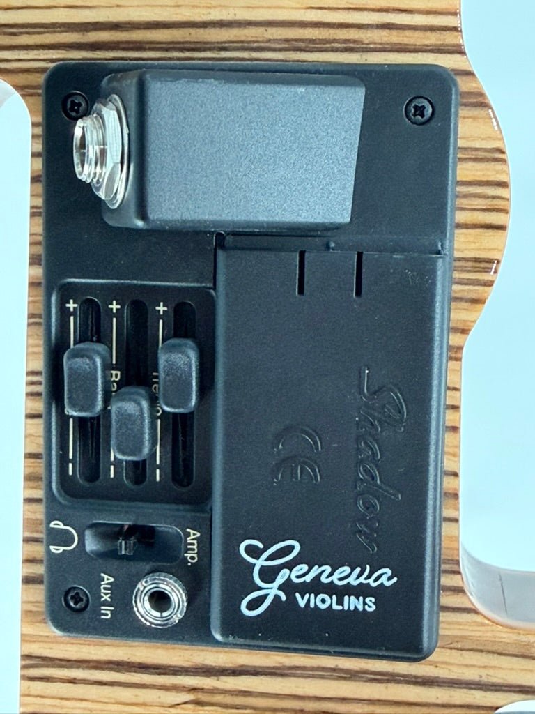 Close-up of the Geneva Electric Violin’s control panel with Shadow preamp, input jack, battery compartment, three sliders, and Amp/Aux In port on its wooden body—professionally set up at Atelier for silent or amplified play.