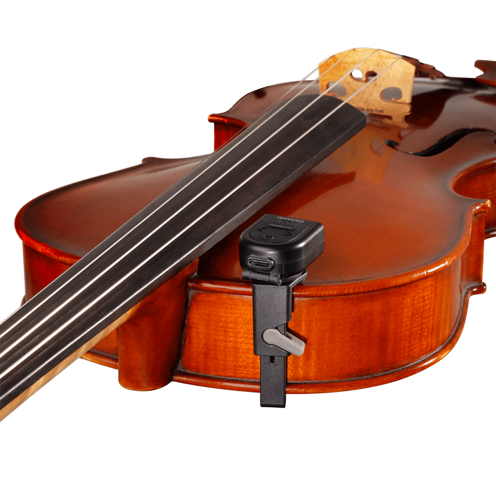 A close-up of a brown violin with a Micro Rechargeable Viola Tuner clipped to its side near the bridge, set against a plain background.