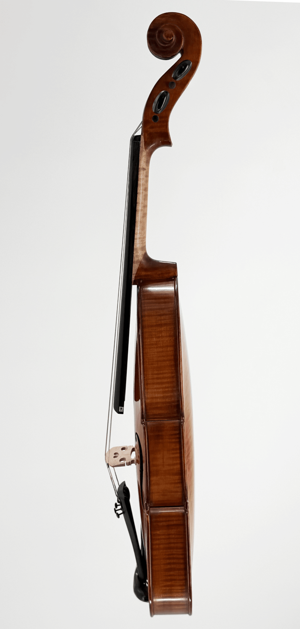A side view of the Octav Mures Viola, crafted from Carpathian tonewoods, stands upright with its polished finish, strings, bridge, and scroll visible against a plain white background.