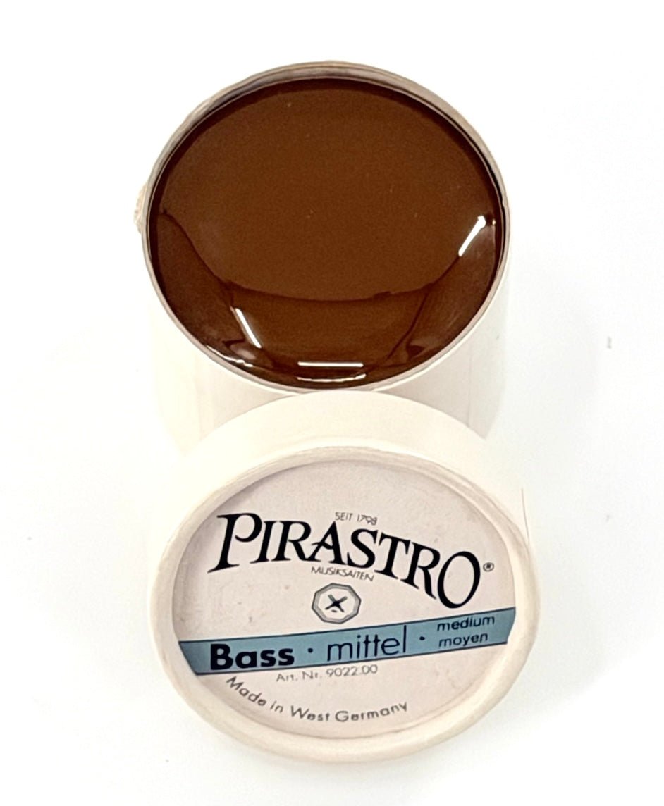 Pirastro Bass Rosin – Medium features a round container with a brown rosin cake and a white lid labeled “Pirastro Bass mittel medium Made in West Germany,” ideal for double bass players seeking medium rosin.
