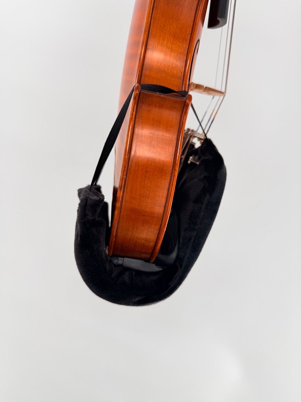 A close-up side view of a violin featuring the Tido Universal Chinrest & Shoulder Pad for Violin and Viola attached to the chin rest, set against a plain white background.